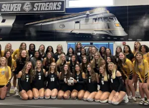 Alt text: Galesburg High School volleyball team poses together in Kimbrough Fieldhouse