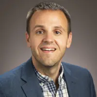 Headshot of Dr. Trent Ford, Illinois State Climatologist, smiling in a blue blazer against a gray background