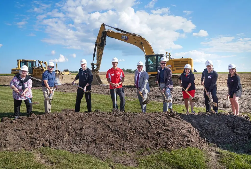 Nine people in hard hats holding shovels at the Carl Sandburg College Charger Center groundbreaking ceremony