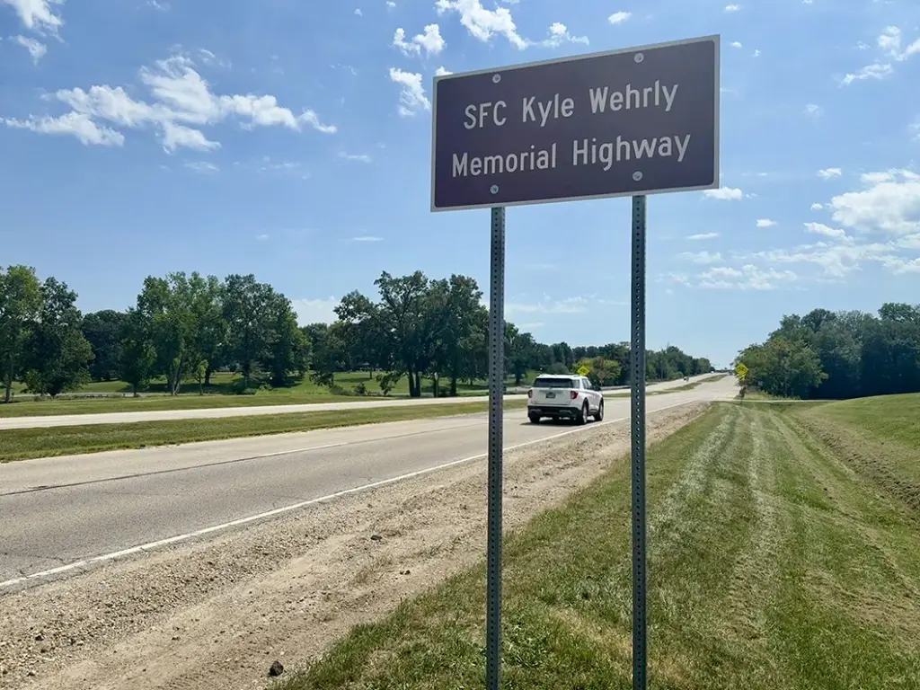 Brown highway sign reading SFC Kyle Wehrly Memorial Highway along U.S. 150