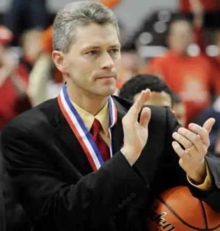 ALT TEXT: Thom Sigel wearing a medal and applauding while holding a basketball