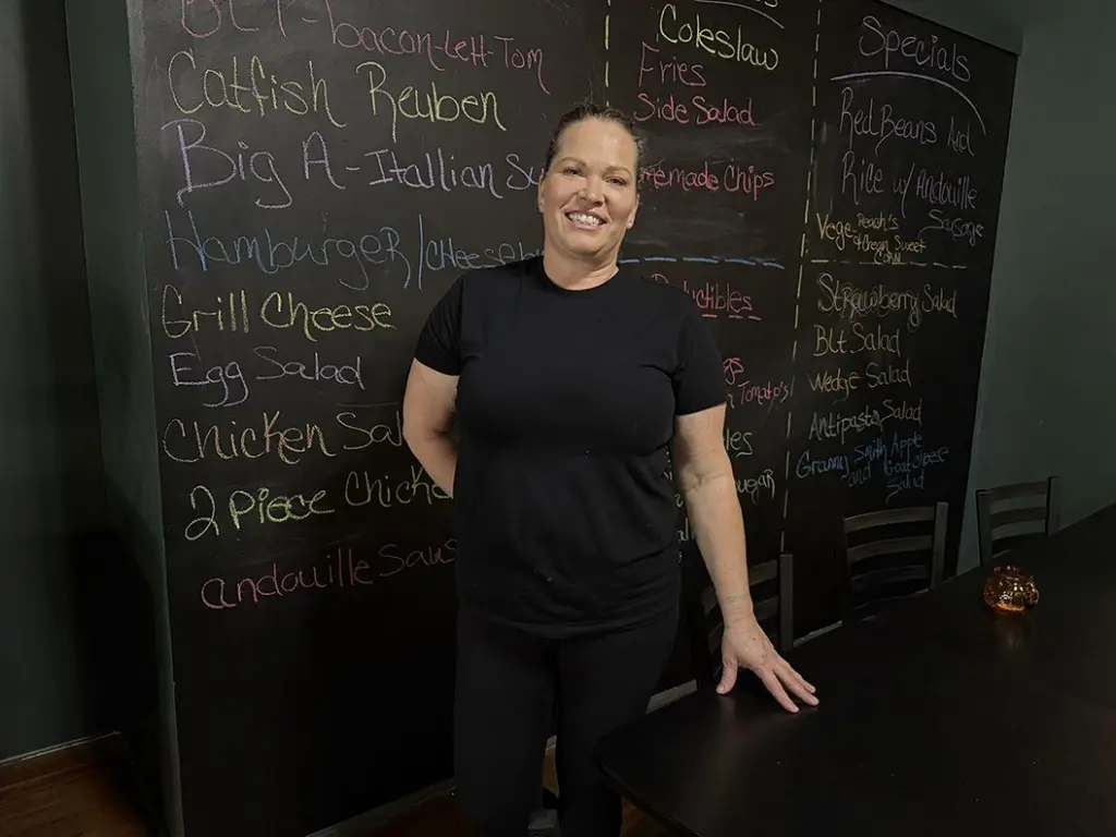 Christie Harris standing in front of a chalkboard menu at The Flavor District