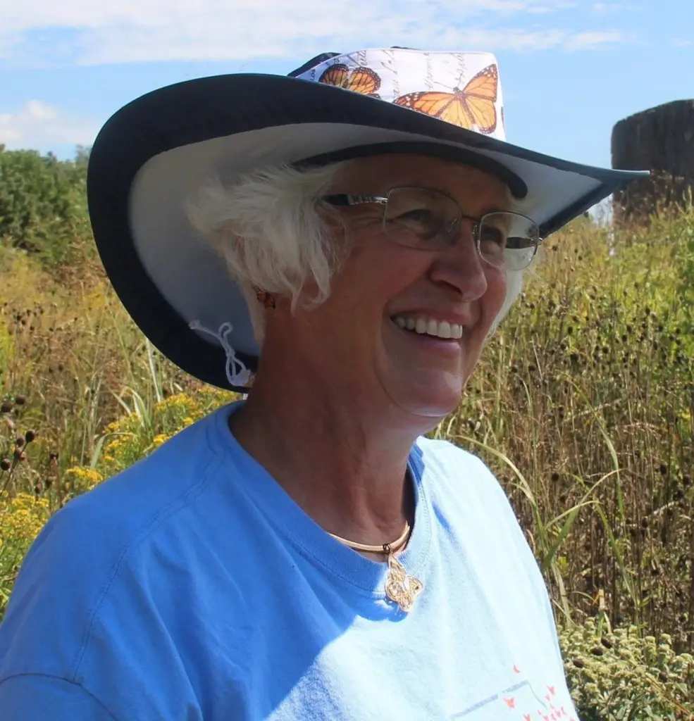 Rhonda Brady wearing a monarch butterfly hat in a prairie field