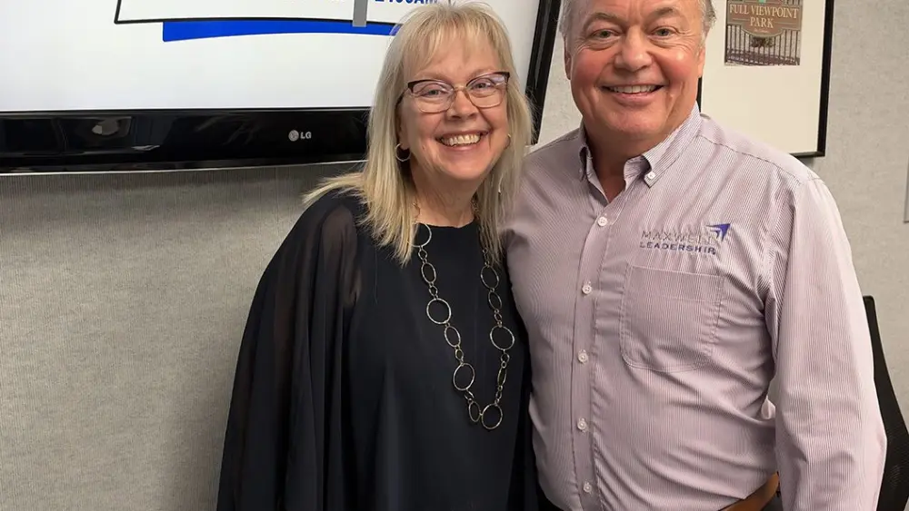 ALT TEXT: Kelly Pointer and Pete Kehoe smile in front of a WGIL logo screen in the radio studio