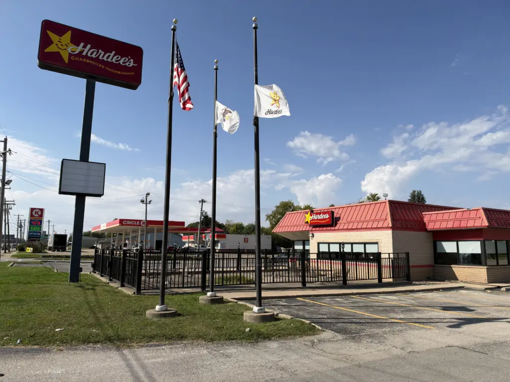 Exterior of the Hardee's restaurant on East Main Street in Galesburg, with its roadside sign, flagpoles and an empty parking lot.