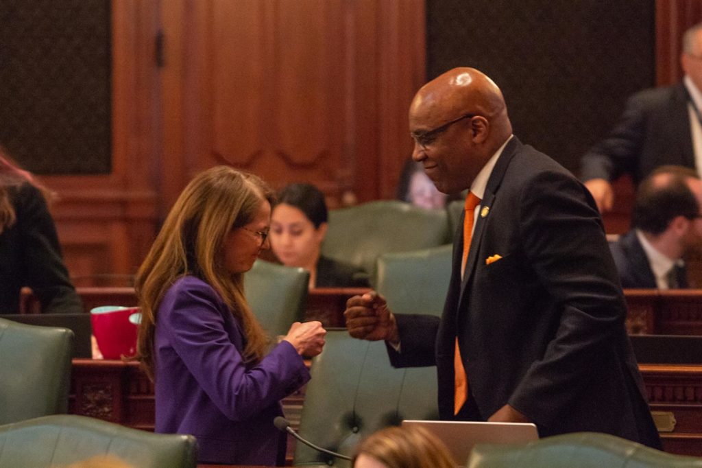 State Rep. Jennifer Gong-Gershowitz, D-Glenview, gets a fist bump Wednesday from Illinois Attorney General Kwame Raoul after she passed a measure giving his office authority to sue gun dealers for deceptive marketing practices. (Capitol News Illinois photo by Jerry Nowicki)