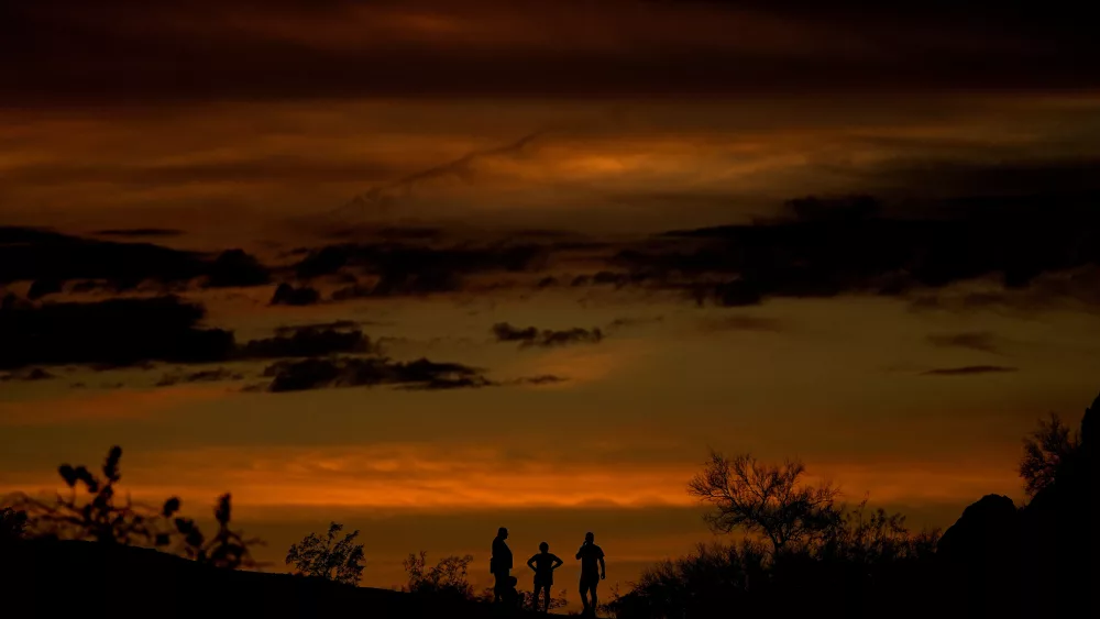 People stand atop a rock formation to watch the sunset, Sunday, July 30, 2023, in Phoenix. Phoenix hit its 31st consecutive day of at least 110 degrees Fahrenheit (43.3 Celsius). The National Weather Service said the temperature climbed to a high of 111 degrees Fahrenheit before the day was through. (AP Photo/Matt York)