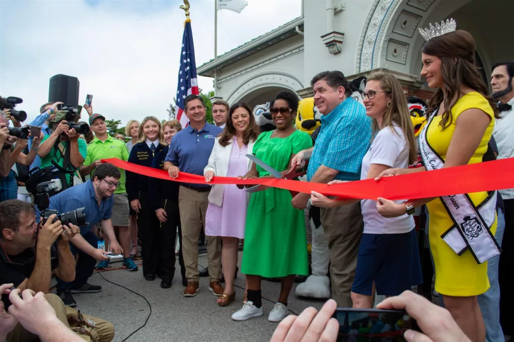 Gov. JB Pritzker, organizers of the Illinois State Fair and others cut the ribbon at the main gate of the Illinois State Fairgrounds last month. (Capitol News Illinois photo by Jerry Nowicki)