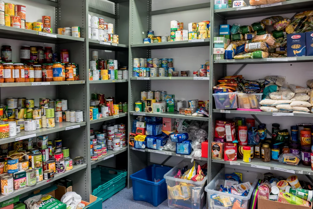 ROTHERHAM, ENGLAND, UK – FEBRUARY 14, 2019: Storage shelves in a Trussell Trust local church food bank warehouse showing a variety of tins and store cupboard essentials ready for food parcels