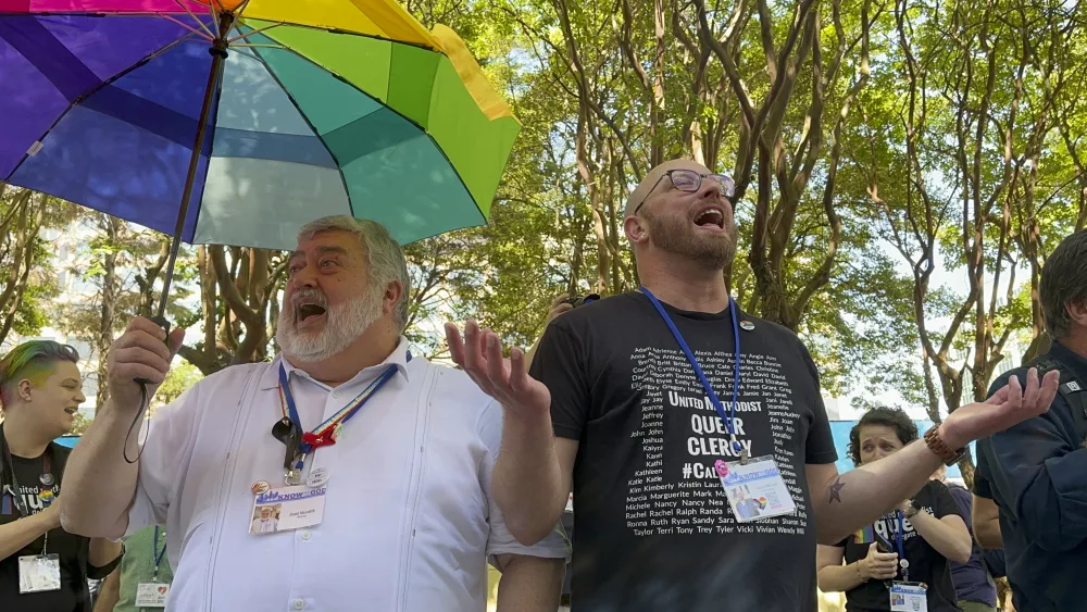 The Rev. David Meredith, left, and the Rev. Austin Adkinson sing during a gathering of those in the LGBTQ community and their allies outside the Charlotte Convention Center, in Charlotte, N.C., Thursday, May 2, 2024. They were celebrating after the General Conference of the United Methodist Church voted to remove the denomination's 52-year-old social teaching that deemed homosexuality "incompatible with Christian teaching." (AP Photo/Peter Smith)