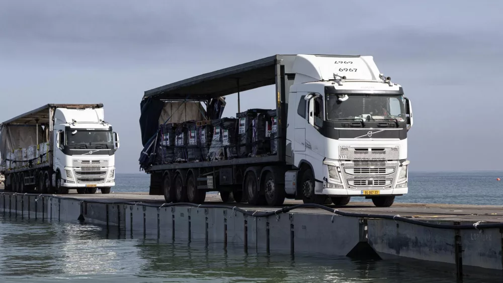 FILE - This image provided by the U.S. Army shows trucks loaded with humanitarian aid from the United Arab Emirates and the United States Agency for International Development cross the Trident Pier before arriving on the beach on the Gaza Strip, May 17, 2024. A string of security, logistical and weather problems have battered the plan to deliver desperately needed humanitarian aid to Gaza through a U.S. military-built pier. Broken apart by strong winds and heavy seas just over a week after it became operational, critics complain that the project hasn't lived up to its initial billing or its $320 million price tag. (Staff Sgt. Malcolm Cohens-Ashley/U.S. Army via AP, File)