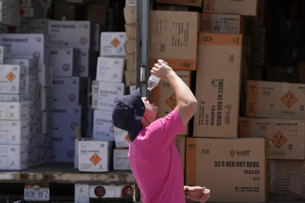 FILE - Wyatt Seymore pours the last drops of liquid from a water bottle into his mouth as he takes a break from unloading a stiflingly hot trailer of fireworks outside Powder Monkey Fireworks ahead of the opening of the stand, Monday, June 17, 2024, in Weldon Spring, Mo. While a heat wave brings the hottest temperatures so far this year to the Midwest and Northeast, forecasters also are discussing heat domes. What's the difference? A heat dome forms when high pressure in the upper atmosphere causes the air below it to sink, heat up and expand. (AP Photo/Jeff Roberson, File)