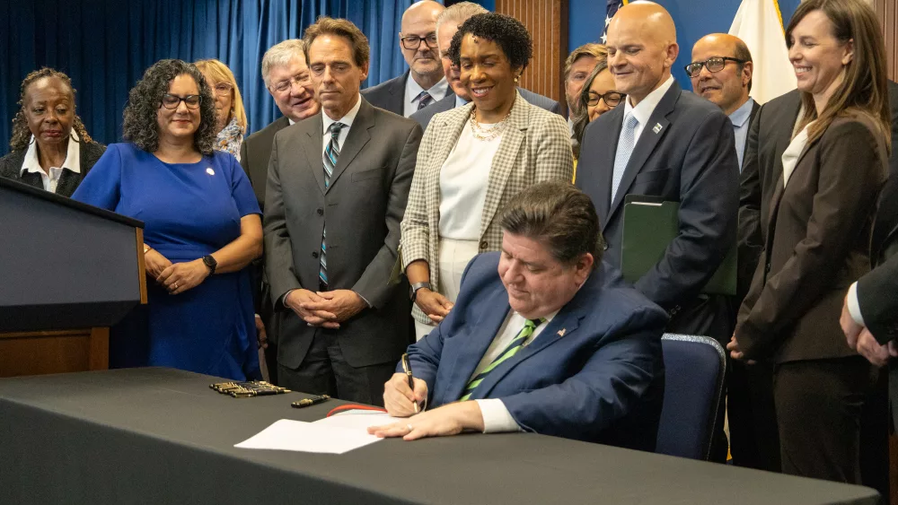 Gov. JB Pritzker signs a package of economic development legislation into law, surrounded by lawmakers, business leaders and representatives of organized labor. (Capitol News Illinois photo by Andrew Adams)