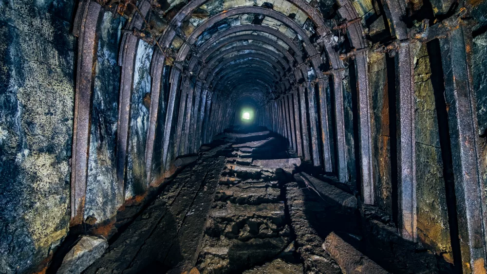 Dark abandoned coal mine with rusty miner stands.