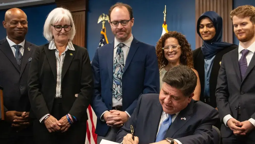 Gov. JB Pritzker signs the Artificial Intelligence Safety Measures Act into law in Chicago on July 6, 2026, surrounded by lawmakers and advocates. (Capitol News Illinois photo by Maggie Dougherty)
