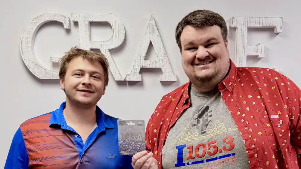 I105.3 office manager Alex Grace presents December Teacher of the Month Zach Turner with his prize.