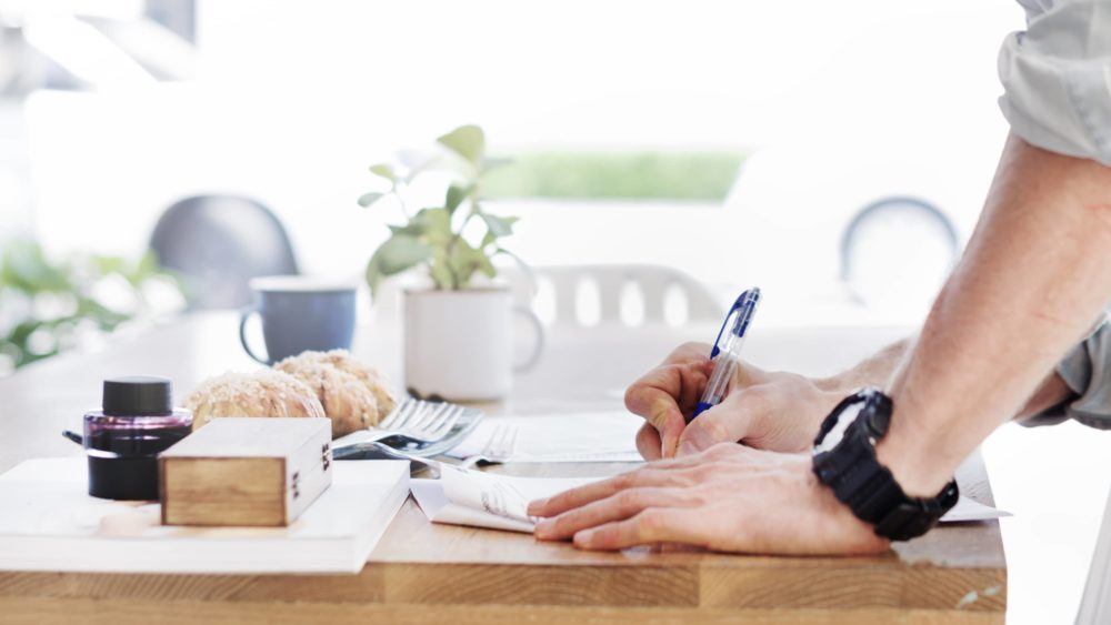 man-writing-document-dinning-table-concept