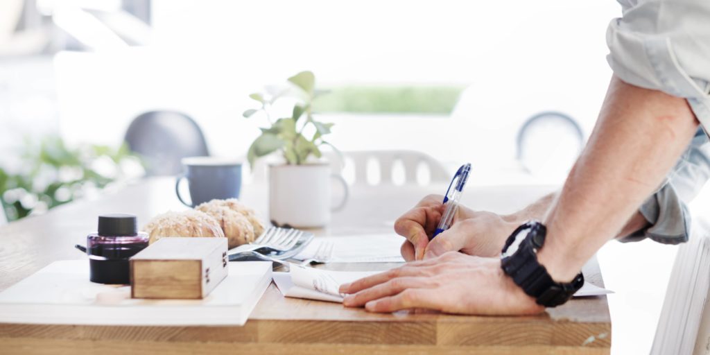 man-writing-document-dinning-table-concept