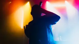 A silhouette of a singer on the stage. Good-looking background^ bright stage lights.