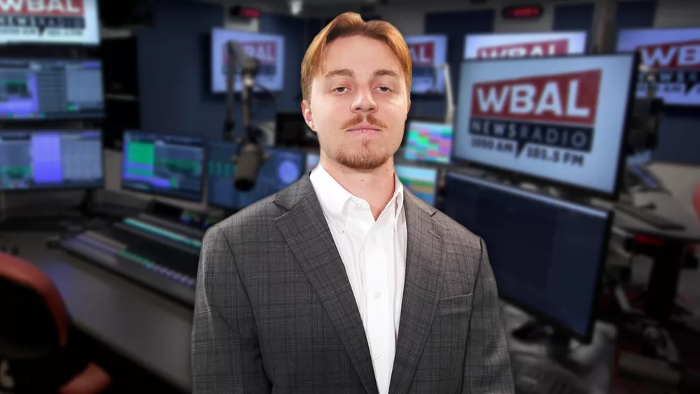 WBAL NewsRadio's Nick Testoni, reporter and host of Saturday's talk show, Sportsline. Nick stands in the WBAL Radio studio in a sports jacket with a straight face.