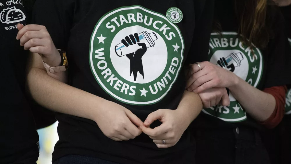 FILE - Starbucks employees and supporters link arms during a union election watch party Dec. 9, 2021, in Buffalo, N.Y. Thousands of U.S. Starbucks workers plan to walk off the job Thursday -- one of the chain's busiest days of the year -- to protest the company's anti-union stance. (AP Photo/Joshua Bessex, File)