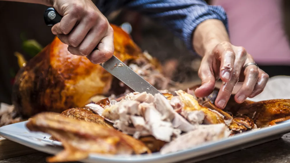 a shot of grease slick hands carving a Thanksgiving turkey