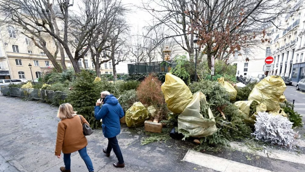 Pedestrians walk past a recycle collected point for Christmas trees, in Paris, on January 8, 2023. - Around 190 collection points are available in Paris to drop off natural Christmas trees. (Photo by Stefano RELLANDINI / AFP) (Photo by STEFANO RELLANDINI/AFP via Getty Images)