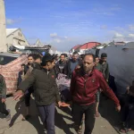 main: Palestinians carry a a body of a person killed in the Israeli bombardment at a building of an UNRWA vocational training center which displaced people use as a shelter in Khan Younis, southern Gaza Strip, Wednesday, Jan. 24, 2024. (AP Photo/Ramez Habboub)