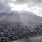 main-v02: FILE - Rays of sunlight pierce through the clouds Thursday, Aug. 10, 2023, above homes burned by wildfires in Lahaina, Hawaii. Days after Maui's wildfires killed scores of people and destroyed 2,000 homes, a shocking claim spread with alarming speed on YouTube and TikTok: The blaze was set deliberately, using futuristic energy weapons developed by the U.S. military. (AP Photo/Rick Bowmer, File)