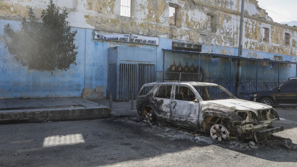 A burned car is seen outside the National Penitentiary in downtown Port-au-Prince, Haiti, Sunday, March 3, 2024. Hundreds of inmates have fled Haiti's main prison after armed gangs stormed the facility overnight. (AP Photo/Odelyn Joseph)