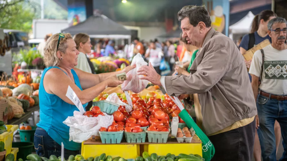 A vendor sells produce to a customer at a farmers market in Baltimore,MD. (Photo by: Edwin Remsberg / VWPics/Universal Images Group via Getty Images)