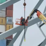 IMG_2521: A worker in a crane basket marks a section of the collapsed Key Bridge that will be cut before it's recovered from the River.  (Image Credit: Phil Yacuboski
Anchor/Reporter
WBAL-AM 1090 and FM 101.5