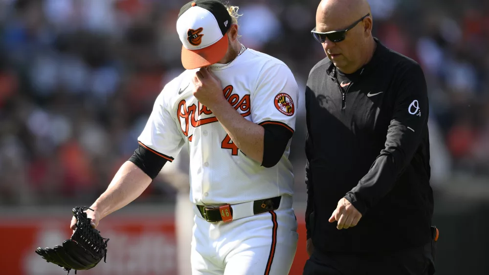Baltimore Orioles relief pitcher Craig Kimbrel, left, leaves alongside trainer Brian Ebel, right, during the ninth inning of a baseball game against the Oakland Athletics, Sunday, April 28, 2024, in Baltimore. (AP Photo/Nick Wass)