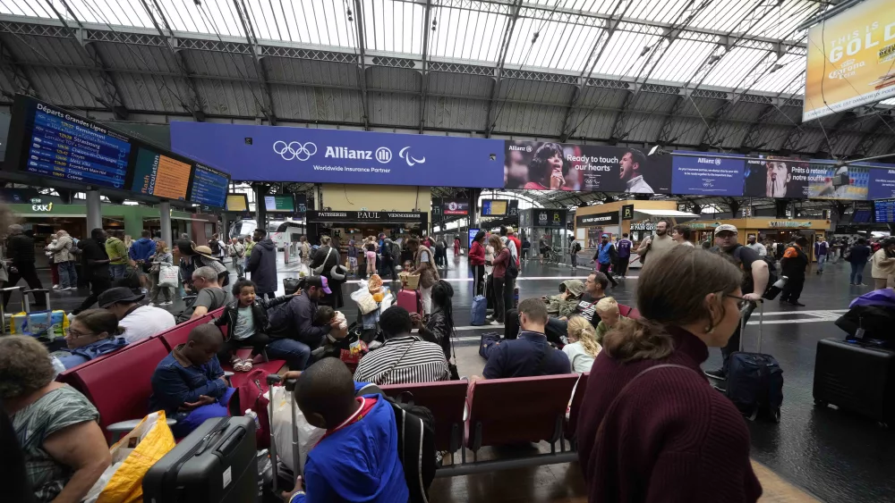Travellers wait at the Gare de L'Est at the 2024 Summer Olympics, Friday, July 26, 2024, in Paris, France. Hours away from the grand opening ceremony of the Olympics, high-speed rail traffic was severely disrupted. (AP Photo/Luca Bruno)