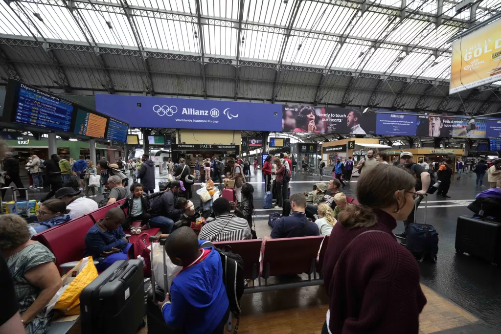 Travellers wait at the Gare de L'Est at the 2024 Summer Olympics, Friday, July 26, 2024, in Paris, France. Hours away from the grand opening ceremony of the Olympics, high-speed rail traffic was severely disrupted. (AP Photo/Luca Bruno)