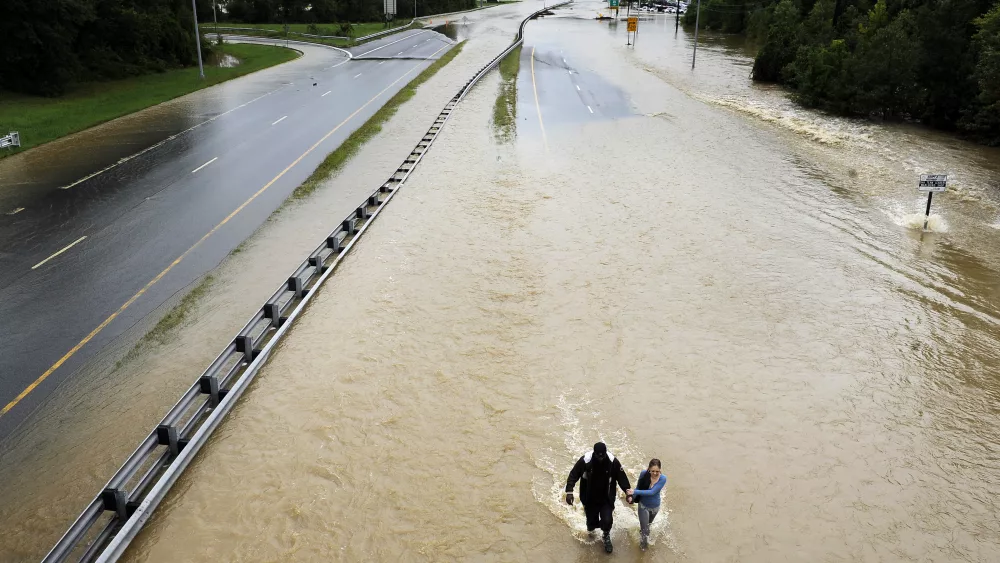 UPPER MARLBORO, MD - SEPTEMBER 8: Ronald Parker walks with Stacey Smith through a flooded Highway 301 on Thursday September 8, 2011 in Upper Marlboro, MD as steady rain fall has caused flooding throughout the area. They had to exit the highway when they were warned not to continue. (Photo by Matt McClain/For The Washington Post via Getty Images)