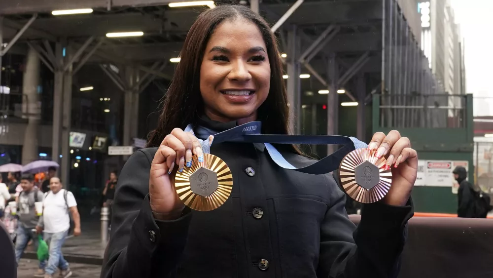 Two-time U.S. Olympic gymnast medalist Jordan Chiles shows her medals after ringing the closing bell at the Nasdaq MarketSite, in New York's Times Square, Thursday, Aug. 8, 2024. (AP Photo/Richard Drew)