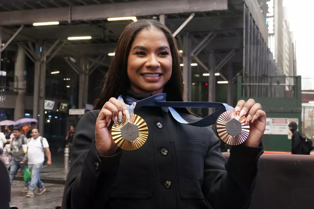 Two-time U.S. Olympic gymnast medalist Jordan Chiles shows her medals after ringing the closing bell at the Nasdaq MarketSite, in New York's Times Square, Thursday, Aug. 8, 2024. (AP Photo/Richard Drew)