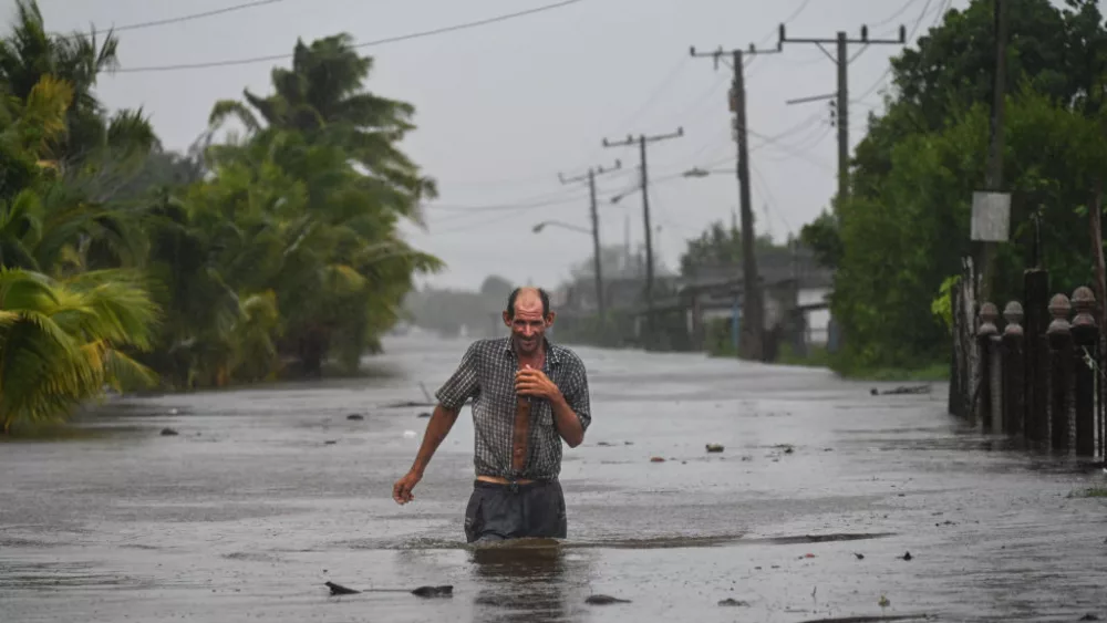 TOPSHOT - A residents of the coastal town of Guanimar in Artemisa province, southwest of Havana, wade trough a flooded street after the passage of Hurricane Helene on September 25, 2024. Tropical Storm Helene became a hurricane mid-morning in the Gulf of Mexico. "Life-threatening storm surge, hurricane-force winds, rainfall and flooding are expected across much of Florida and the southeastern United States," the Miami-based National Hurricane Center (NHC) said in its latest bulletin. (Photo by YAMIL LAGE / AFP) (Photo by YAMIL LAGE/AFP via Getty Images)