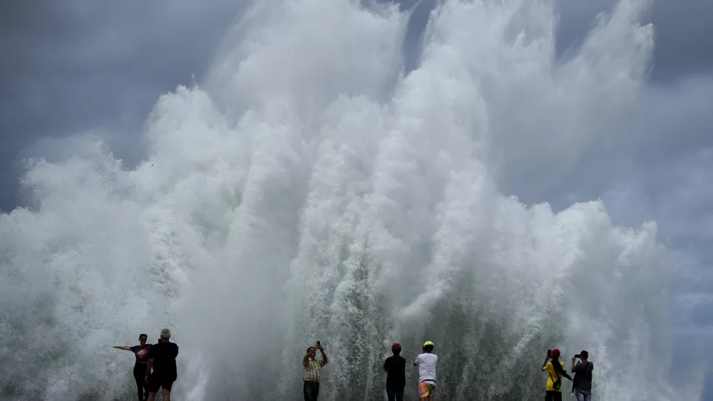 People take photos of the spray from waves crashing against the Malecon seawall, brought by the passing of Hurricane Milton in the Gulf of Mexico, in Havana, Cuba, Wednesday, Oct. 9, 2024. (AP Photo/Ramon Espinosa)