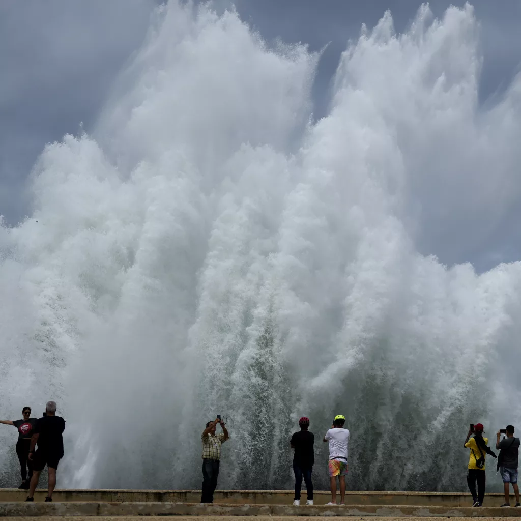 People take photos of the spray from waves crashing against the Malecon seawall, brought by the passing of Hurricane Milton in the Gulf of Mexico, in Havana, Cuba, Wednesday, Oct. 9, 2024. (AP Photo/Ramon Espinosa)