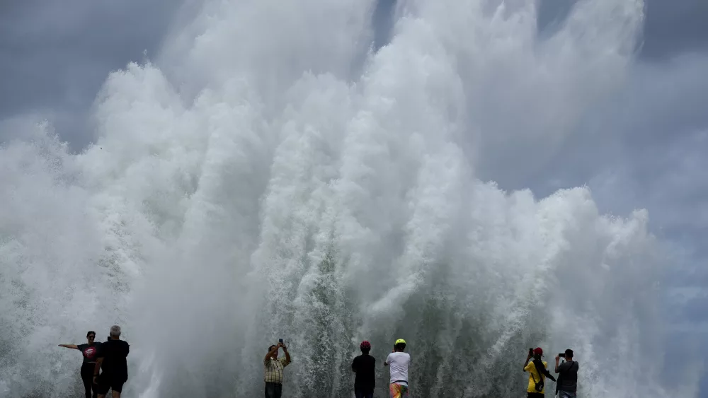 People take photos of the spray from waves crashing against the Malecon seawall, brought by the passing of Hurricane Milton in the Gulf of Mexico, in Havana, Cuba, Wednesday, Oct. 9, 2024. (AP Photo/Ramon Espinosa)