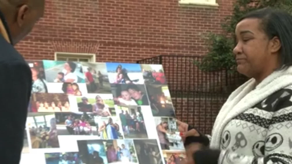 image of daughter of woman who was shot and killed in annapolis parkign lot on october 3 - woman is seen next to a collage of her mother, visibily crying. - Allison McIntyre was helping a woman get gas when that woman shot and killed her in Annapolis, according to McIntyre's daughter. McIntyre's body was found inside her car on Oct. 3 in the parking lot of the Annapolis Marketplace.