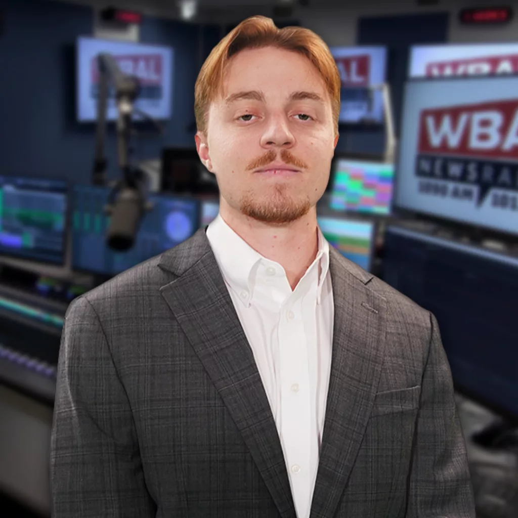 WBAL NewsRadio's Nick Testoni, reporter and host of Saturday's talk show, Sportsline. Nick stands in the WBAL Radio studio in a sports jacket with a straight face.