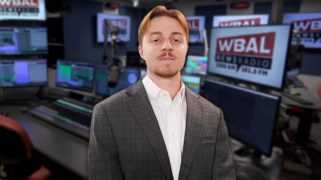 WBAL NewsRadio's Nick Testoni, reporter and host of Saturday's talk show, Sportsline. Nick stands in the WBAL Radio studio in a sports jacket with a straight face.