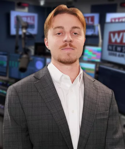 WBAL NewsRadio's Nick Testoni, reporter and host of Saturday's talk show, Sportsline. Nick stands in the WBAL Radio studio in a sports jacket with a straight face.