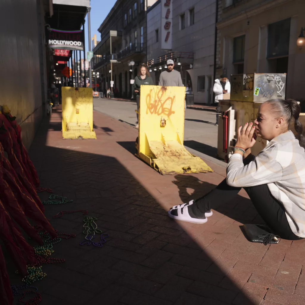 Samantha Petry, who works in the area, visits a flower memorial set up on Canal and Bourbon Street, Thursday, Jan. 2, 2025 in New Orleans. (AP Photo/George Walker IV)