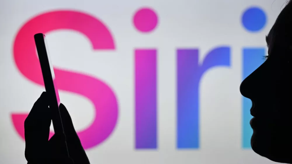 EDMONTON, CANADA - APRIL 28: An image of a woman holding a cell phone in front of the Siri logo displayed on a computer screen, on April 29, 2024, in Edmonton, Canada. (Photo by Artur Widak/NurPhoto via Getty Images)