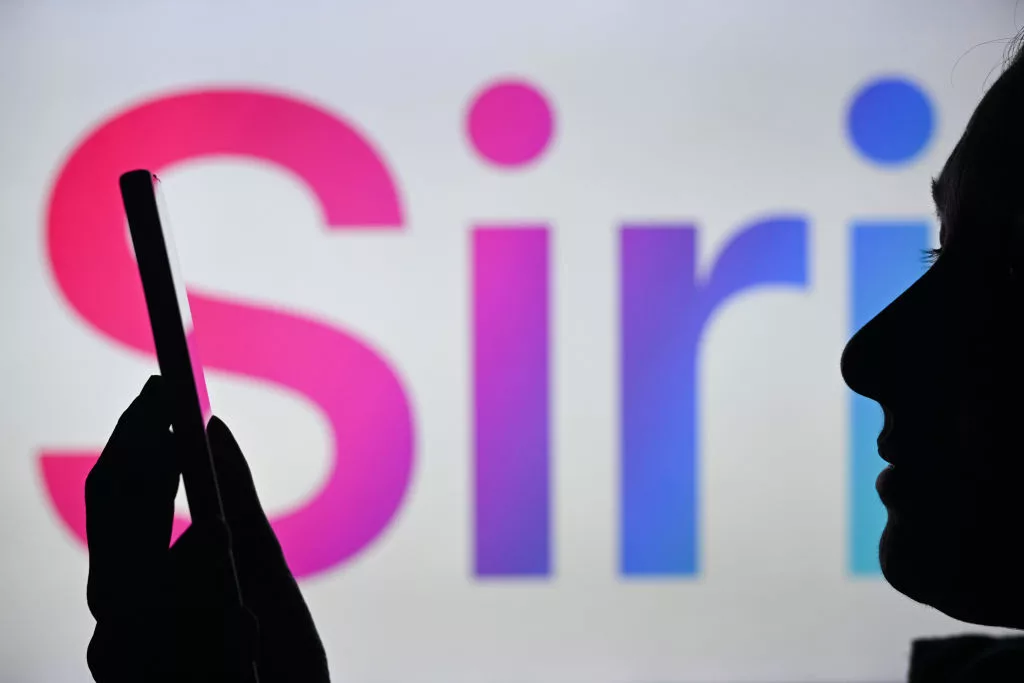 EDMONTON, CANADA - APRIL 28: An image of a woman holding a cell phone in front of the Siri logo displayed on a computer screen, on April 29, 2024, in Edmonton, Canada. (Photo by Artur Widak/NurPhoto via Getty Images)