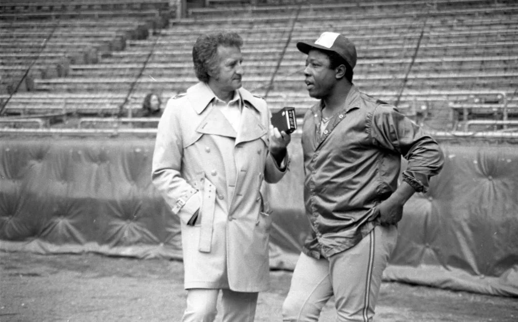 CLEVELAND, OH - APRIL 19, 1975: Bob Uecker (L) interviews Hank Aaron #44 of the Milwaukee Brewers prior to a game on April 19, 1975 against the Cleveland Indians at Cleveland Municipal Stadium in Cleveland, Ohio. (Photo by 1975 Diamond Images via Getty Images)